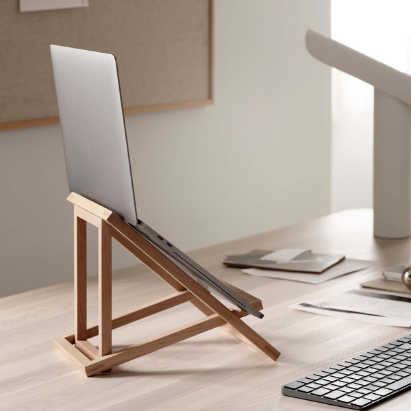 Foldable laptop stand in solid oak holding a computer